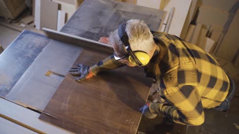 A-male-carpenter-uses-a-saw-in-a-carpentry-workshop.